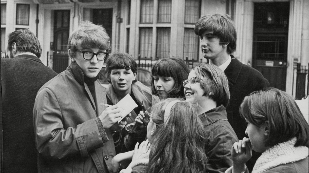 a man with glasses surrounded by a crowd of people